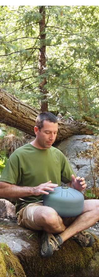 a man playing a steel tongue drum in the forest